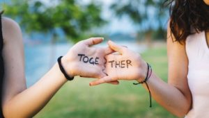 Two people holding hands with the word together written on palm