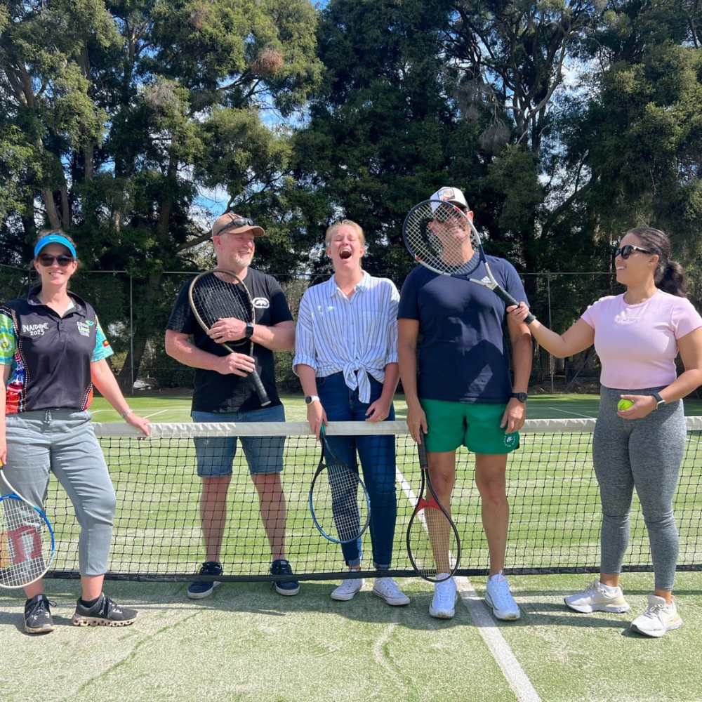 five people holding tennis racquets and smiling