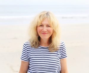 A smiling woman stands on a beach